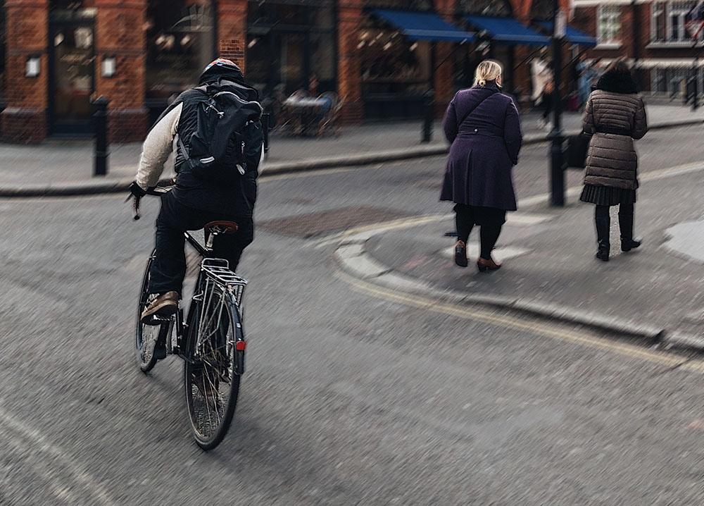 A cyclist rides rapidly through city streets