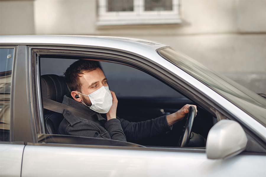 Man wearing a mask in a car because of Covid