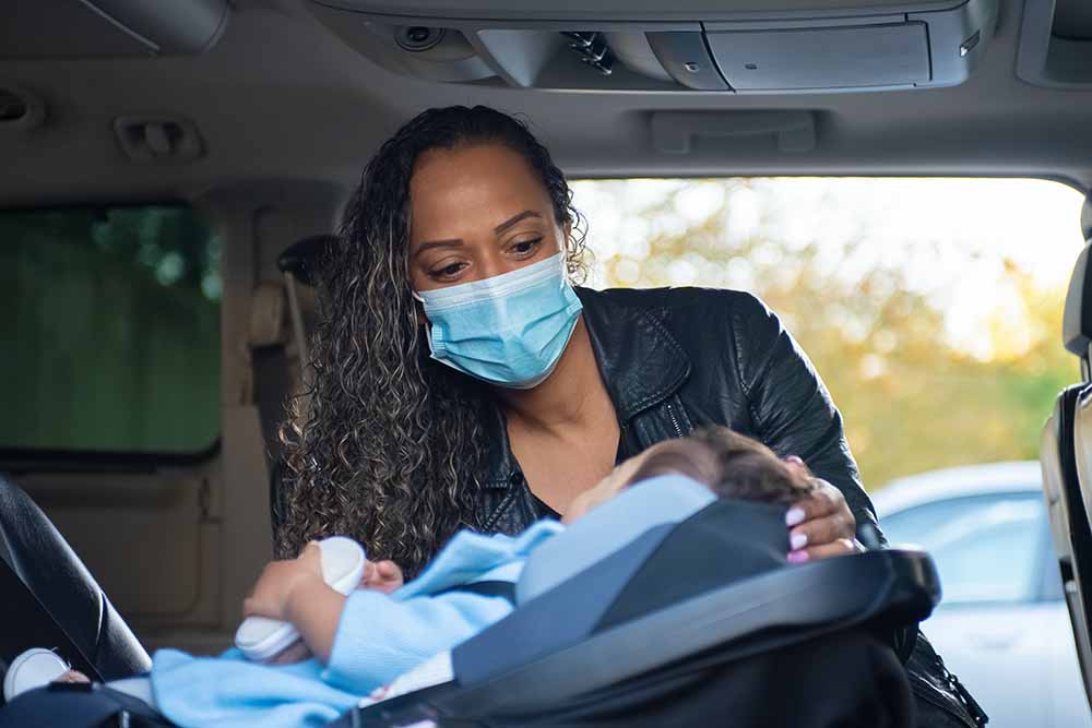 A woman attempts to remove her child from a car in a tight parking space