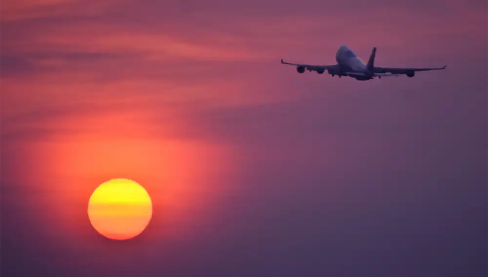 A plane flies into the sunset, suggesting a passenger is carrying ashes of a loved one to be scattered on final journey